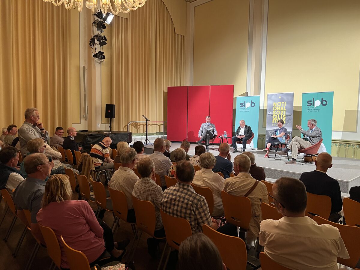 Podiumsdiskussion vom 19. Juni 2025 mit Oberst Dr. Dr. Rudolf J. Schlaffer, Dr. Hans-Wilhelm Pietz, Dr. Annemarie Franke und Moderator Dr. Roland Löffler (v.l.n.r.) in der Aula des Augustum-Annen-Gymnasiums, Foto: Ina Rueth